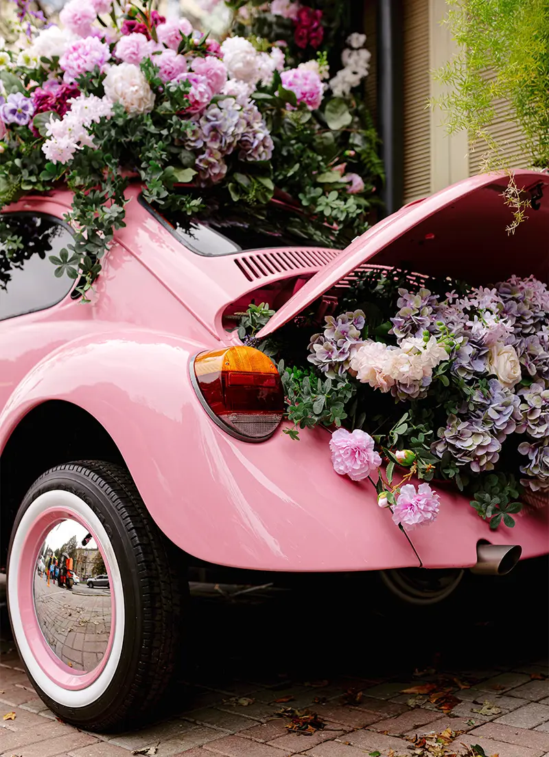 Voiture rose décorée avec des fleurs pour un mariage